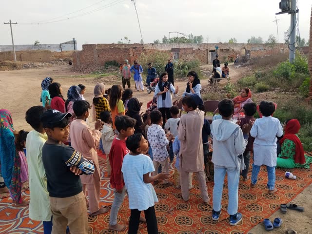 Two young women leading children in clapping on a patterned rug