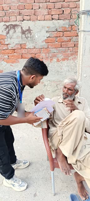 A young volunteer listens as an older man talks over a booklet they are reading together