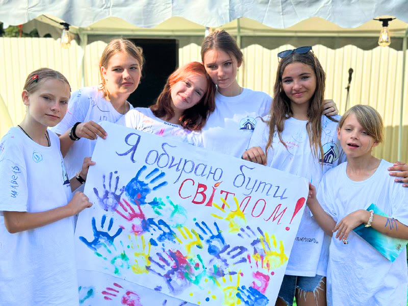 Teenagers at a S4HK youth camp holding a hand-painted banner that reads "I choose to be a light" in Ukrainian